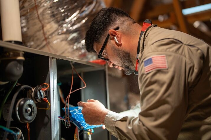 A technician inspecting and repairing an HVAC unit