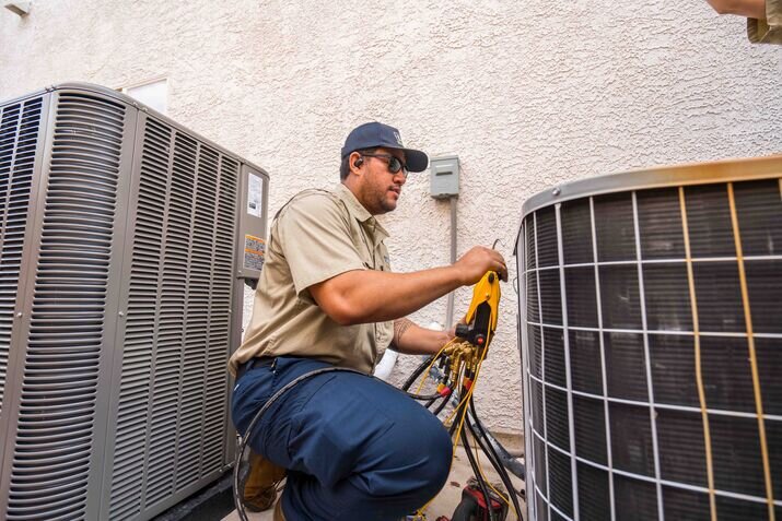 A technician performing a tune up on an AC Unit