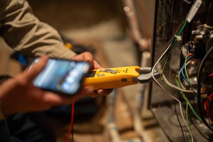 A technician inspecting wires on an HVAC unit
