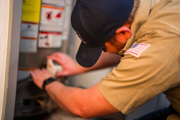 A technician performing a flush on a water heater